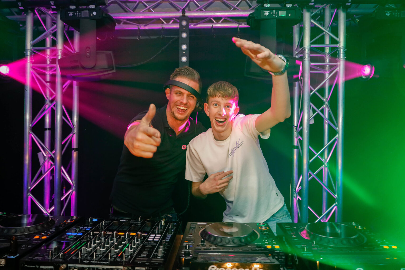 Twee dj's met apparatuur op podium.